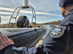 policjant oparty ręką o łódź, patrzy w stronę jeziora