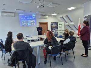osoby siedzące na sali odpraw a przed nimi stoi Komendant