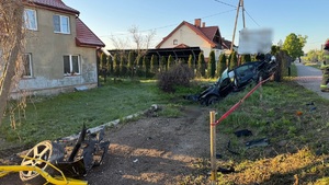 Z lewej strony widać dom, naprzeciwko jego w rowie stoi rozbity samochód osobowy