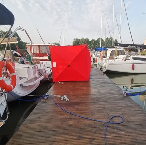 zacumowane łodzie przy pomoście i rozstawiona czerwona ścianka na pomoście
