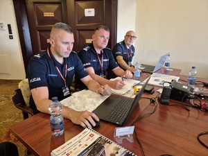 3 policjantów siedzących przy stole w Centrum Zarządzania Rajdem