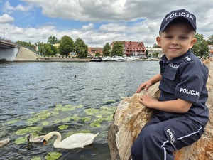 chłopiec przebrany za policjanta siedzi nad jeziorem
