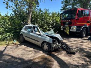 rozbity samochód stojący na drodze a po jego prawej stornie wóz strażacki