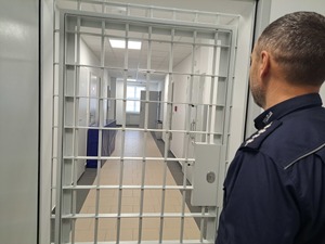 policjant stojący przed pomieszczeniem dla osób zatrzymanych