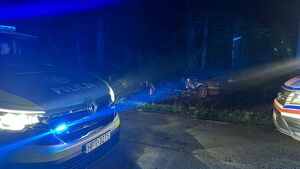 nocą przód radiowozu a w głębi widać w rowie samochód