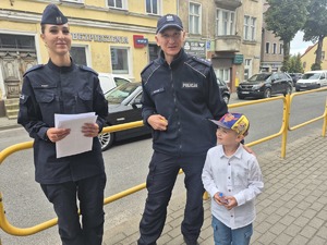 dzielnicowy stoi przy uczniu, obok nich stoi policjantka z ulotkami