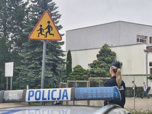 dach radiowozu w tle policjantka i szkoła