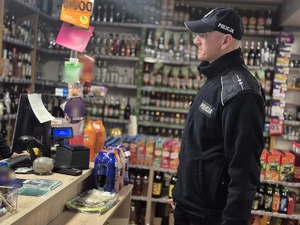 policjant w sklepie alkoholowym rozmawia z ekspedientką