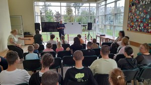 policjant stoi na sali a przed nim siedzą uczniowie