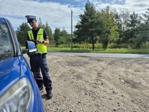 policjant rozmawiający z kierowcą zatrzymanym do kontroli drogowej w niebieskim samochodzie