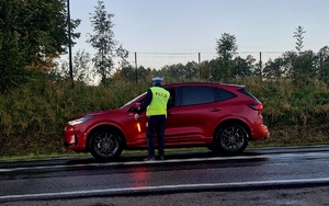 policjant stojący na drodze, kontroluje pojazd