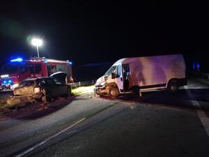 Zdjęcie przedstawia dwa rozbite auta oraz wóz strażacki znajdujące się na drodze ekspresowej w porze nocnej.