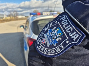 emblemat ruchu drogowego KPP Mrągowo a w tle radiowóz