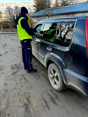 policjant stojący przy samochodzie z alkomatem
