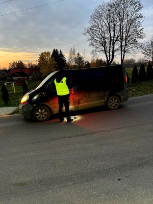 policjant stojący przy samochodzie z alkomatem