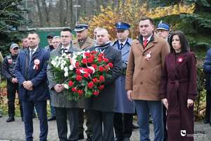 stojący wśród samorządowców policjant