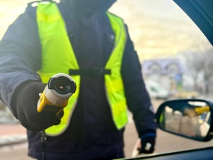 Obraz przedstawia policjanta przeprowadzającego badanie stanu trzeźwości kierującego.