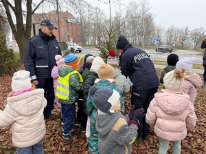dzieci z policjantami ubierają odblaskami choinkę
