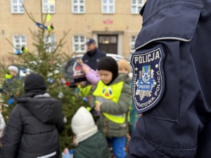 dzieci z policjantami ubierają odblaskami choinkę