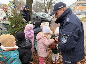 dzieci z policjantami ubierają odblaskami choinkę