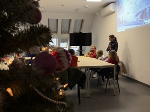 z lewej strony widać fragment choinki, z prawej strony przed dziećmi stoi policjantka