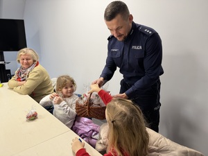 Policjant częstuje dzieci słodyczami z koszyczka