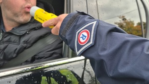 mężczyzna siedzący w radiowozie, dmuchający w alkomat