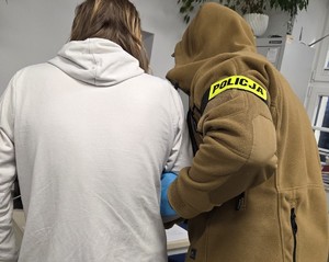 nieumundurowany policjant stoi przy zatrzymanej kobiecie