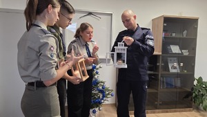 Komendant trzyma lampion ze świeczką, a harcerze odpalają od swojego lampiona płomień