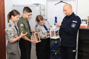 Komendant trzyma lampion ze świeczką, a harcerze odpalają od swojego lampiona płomień