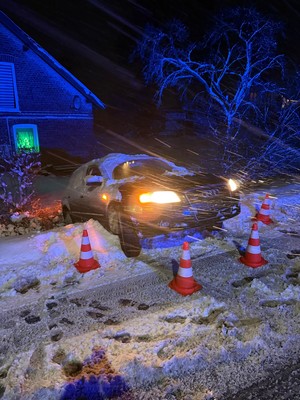 zimą, na zaśnieżonej drodze samochód osobowy stojący przodem w kierunku drogi a tyłem w rowie