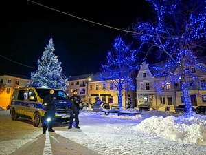 dwóch policjantów stojących na tle radiowozu. Na dworze jest zima i dużo śniegu