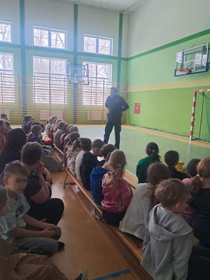 dzielnicowy stoi na sali przed grupką dzieci