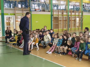 dzielnicowy stoi na sali przed grupką dzieci