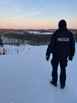 policjant zimą patrzy na stok narciarski