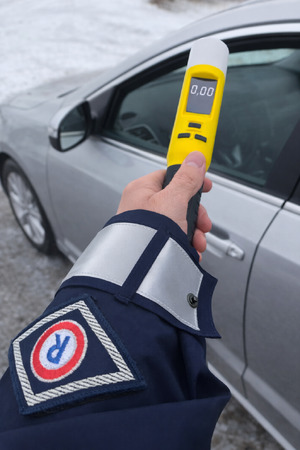 Zdjęcie przedstawia policjanta trzymającego w ręku alkomat.
