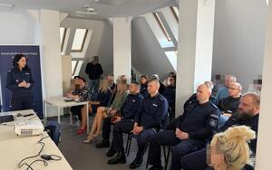 Zdjęcie przedstawia policjantkę prowadzącą wykład oraz słuchaczy wykładu.