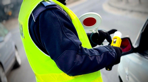 Zdjęcie przedstawia policjanta trzymającego w ręku alkomat.