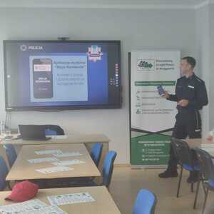 Zdjęcie przedstawia policjanta prezentującego aplikację MOJA KOMENDA