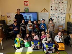 Zdjęcie przedstawia policjanta wraz z uczniami uczestniczącymi w zajęciach.