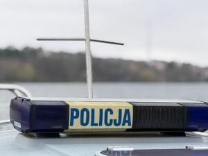 Zdjęcie przedstawia łódź policyjna na tle jeziora.