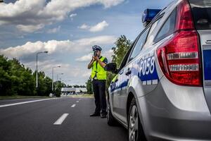 Zdjęcie przedstawia policjanta mierzącego prędkość.
