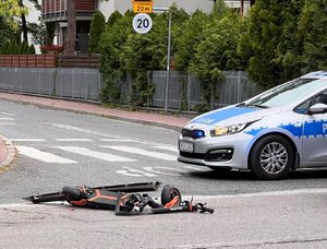 Zdjęcie przestawia radiowóz oraz leżąca przed nim na jezdni hulajnogę elektryczną.