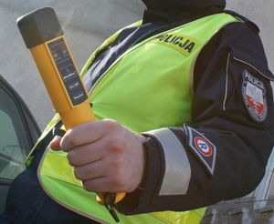 Zdjęcie przedstawia policjanta trzymającego w ręku alkomat.