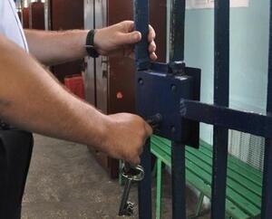 Zdjęcie przedstawia policjanta zamykającego kraty.