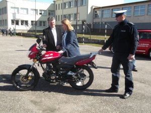 uczennica przy motorowerze wraz z policjantem i egzaminatorem